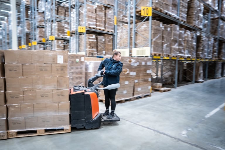 Woman transporting packages inside warehouse